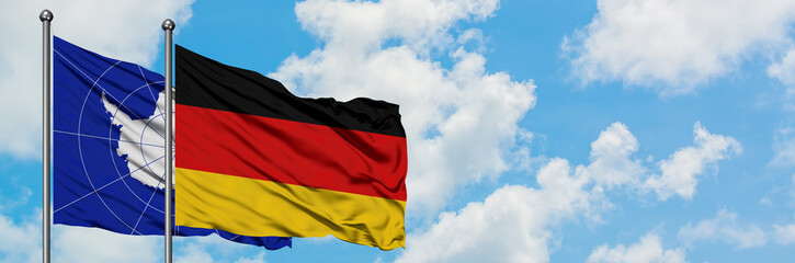 Antarctica and Germany flag waving in the wind against white cloudy blue sky together. Diplomacy concept, international relations.