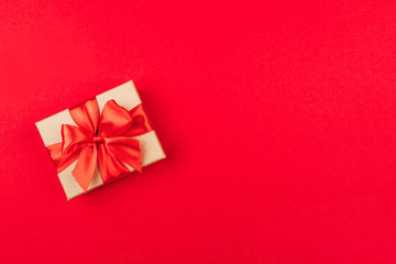 Cardboard gift box with bow on red background.