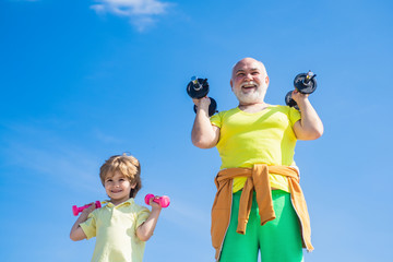 We exercise every day. Grandfather and grandson with dumbbells in hands. Portrait of senior man and...