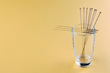 Silver needles for traditional Chinese acupuncture medicine. Yellow background. Close-up. Full depth of field.