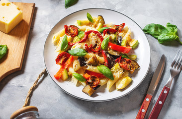 Pasta with grilled vegetables - zucchini, eggplant, pepper ant tomato on concrete background