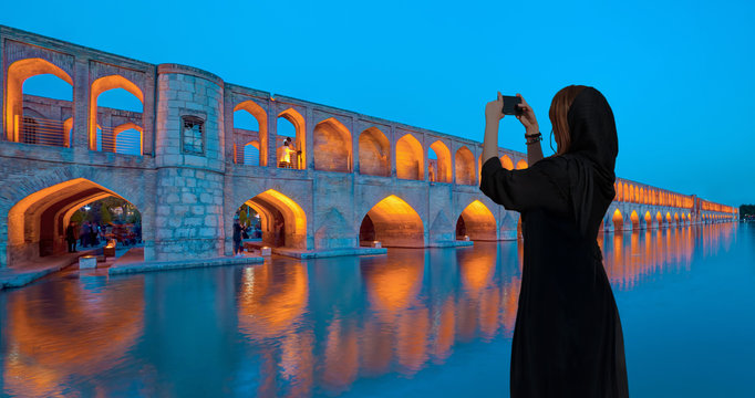 Beautiful Iranian girl wearing abaya with taking selfie - Si o seh pol Bridge at twilight blue hour (33-eyed bridge) - Esfahan, Iran