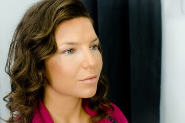 Naklejka premium side portrait of beautiful young woman in beauty salon waiting for make up treatment looking aside of camera