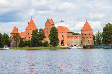 Yachts and medieval gothic Trakai Island Castle with stone walls and towers with red tiled roofs in lake Galve, Lithuania. Trakai Castle is one of major tourist attractions of Lithuania