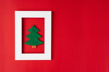 New Year tree in a white frame on a red background. Christmas concept. Greeting card for christmas present. Christmas layout of things.