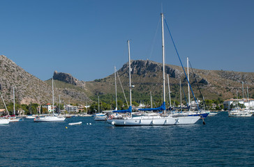 Fototapeta na wymiar Port de Pollenca Majorca view of yacht's moored in the beautiful bay of Pollensa with a lovely backdrop of mountains.