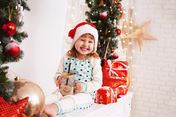 little girl in pajamas and Santa hat drinking cocoa milk