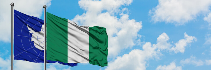 Obraz premium Antarctica and Nigeria flag waving in the wind against white cloudy blue sky together. Diplomacy concept, international relations.
