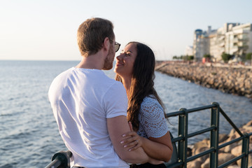 couple snuggling on pier at sunset 