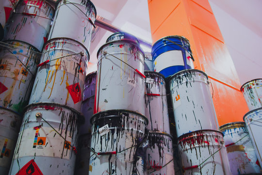 A collection of paint cans, glue buckets, mastic and toxic and hazardous material stacked