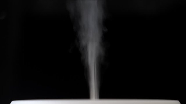 Diffuser for essential oils diffusing steam on black background. Nobody
