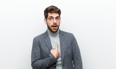 young manager man looking shocked and surprised with mouth wide open, pointing to self against...