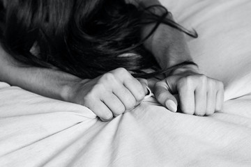 Woman's hands pulling white sheets in ecstasy, orgasm