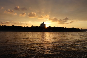 Naklejka premium orange sunset over the river with dark church silhouetted on the