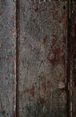 Close-up of a weathered and aged wooden door, wall or wood panelling with red paint peeling off.