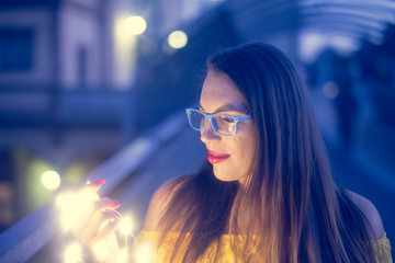 Junge Frau mit blauer Brille schaut in eine Lichterkette