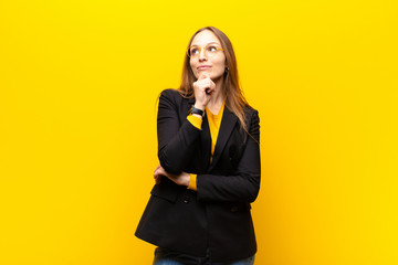 young pretty businesswoman feeling thoughtful, wondering or imagining ideas, daydreaming and...