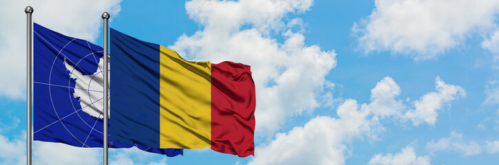 Antarctica and Romania flag waving in the wind against white cloudy blue sky together. Diplomacy concept, international relations.