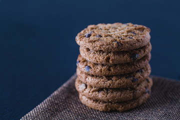 Stacked oatmeal handmade chocolate cookies on black slate plate isolated