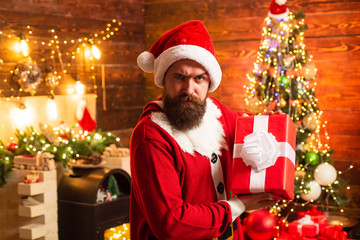 Delivery gifts. Gift emotions. Santa man holding gift. Hipster in red Santa hat holding present.