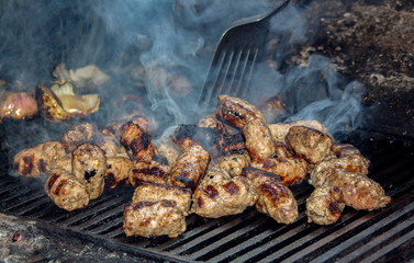 Small kebabs (pork and veal mince, typical Balkan cuisine) grilled in a mobile kitchen.  Amid the smoke and slotted spatula.