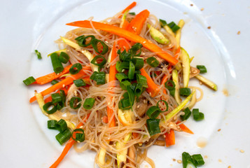 Portion vegetable salad with noodles. With mushrooms, carrots, zucchini, carrots, sesame seeds, and green onions.