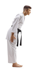 Young guy in karate kimono with black belt bowing