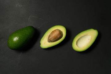 Fresh, raw avocado sliced on a black