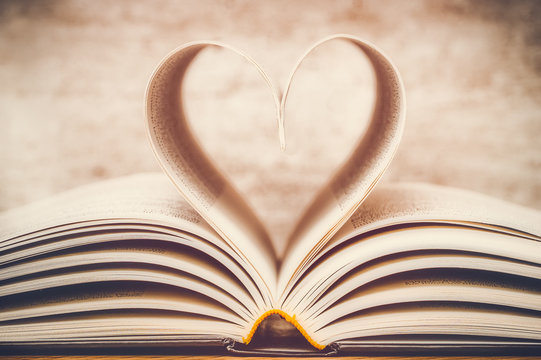 Heart shape made with book pages closeup. Toned and dreamy image. Love of reading, novel, stories, imaginary, knowledge, studies concept.