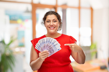 people and finances concept - happy woman in red dress showing euro money banknotes over office...