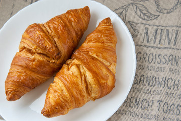 Fresh baked croissants on white plate. French breakfast