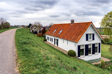 Fototapeta na wymiar Houses behind the river dikes near Sleeuwijk (NL) on a day with overcast