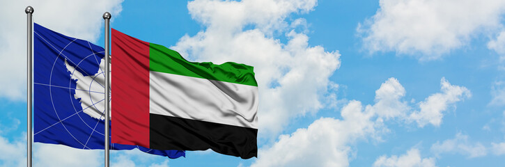 Fototapeta na wymiar Antarctica and United Arab Emirates flag waving in the wind against white cloudy blue sky together. Diplomacy concept, international relations.