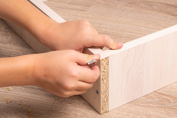 Hands of a craftsman assembling wood chipboard furniture. Tightening SCREW