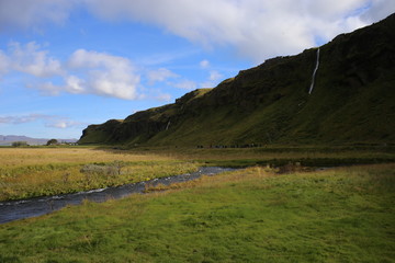 Fototapeta na wymiar Paisaje en Islandia con agua y campo verde y cielo azul