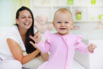  Smiling mom and baby lying in bed, baby in front , looking at camera.Shallow doff  