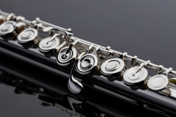 Naklejka premium A shiny silver plated flute on a reflective surface. An instrument common in a symphony orchestra