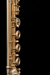 A part of a gold plated flute on a black background. An instrument common in the symphony orchestra