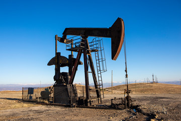 Oil Pumpjack Operating in Open Arid Energy Field Under Clear Sky
