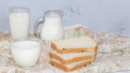 Fresh simple homemade kefir drink, milk and bran bread on a gray concrete background with copy space. Probiotic cold sour milk drink, healthy nutrition concept, 
