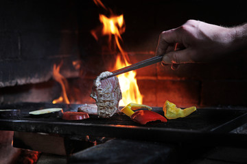A piece of chicken is grilled. Open fire in the oven. The concept of cooking on the grill. Macro photo. Photo without a face.