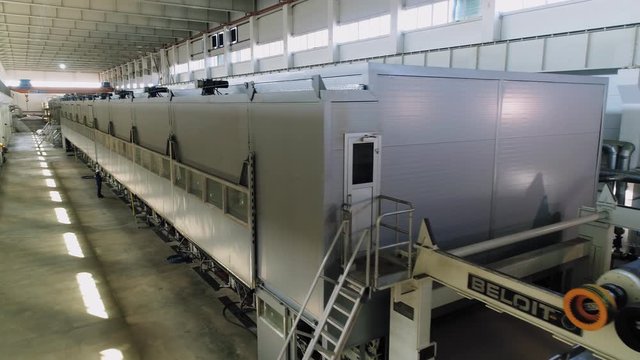 brown paper rolls in production line and worker at plant