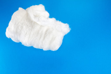 large roll of medical cotton on blue background close-up