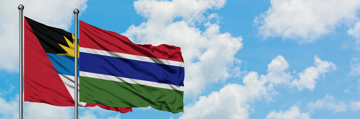 Antigua and Barbuda with Gambia flag waving in the wind against white cloudy blue sky together. Diplomacy concept, international relations.