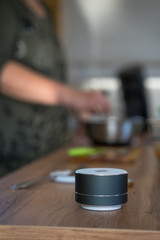 Fototapeta na wymiar Smart ai speaker with woman cooking in the background. Smart home concept