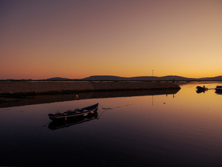 Small wooden fishing boat at a harbor at sunset, Soft warm color, Calm and peaceful atmosphere.