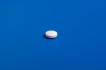 one white round pill on a blue background. Copy space for text.