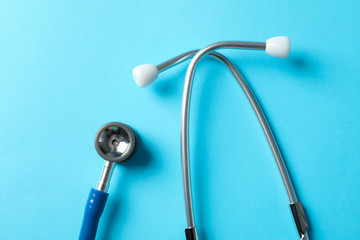 Stethoscope on blue background, top view and space for text