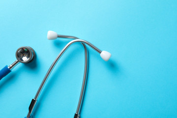 Stethoscope on blue background, top view and space for text