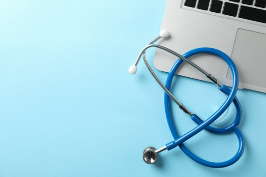 Stethoscope and laptop on blue background, space for text